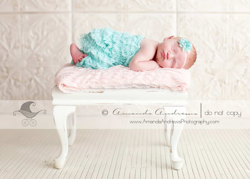 newborn girl posed on bench with ruffle bloomers photograph