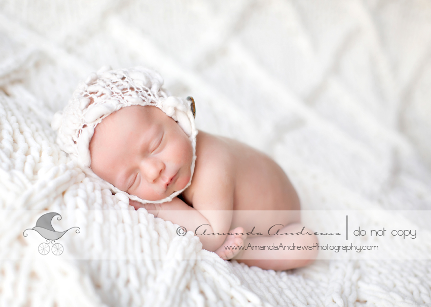 picture of newborn infant on white blanket with white knit hat