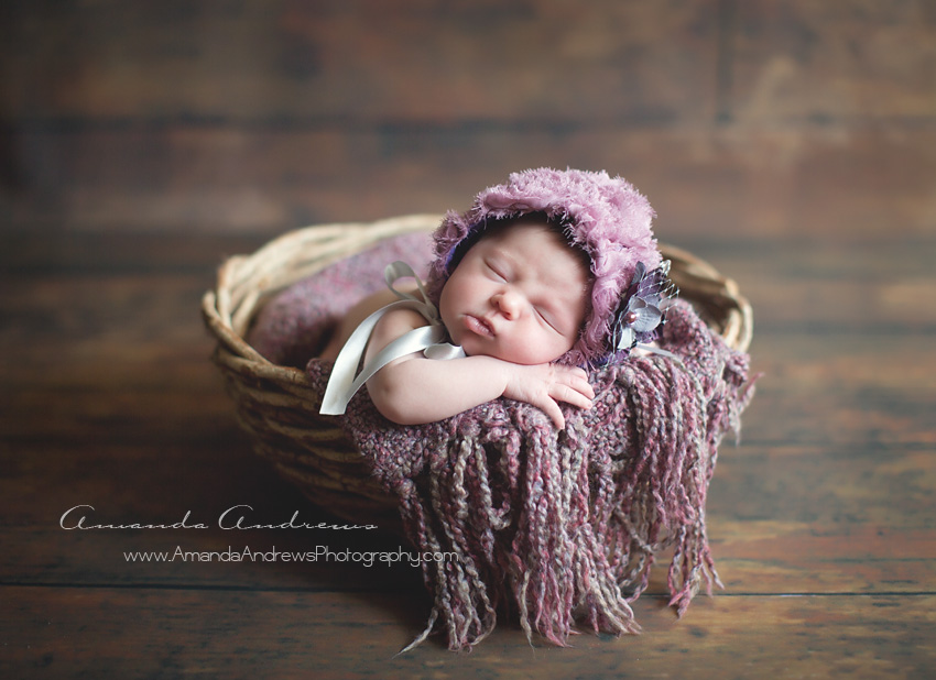 newborn girl in basket with purple hat