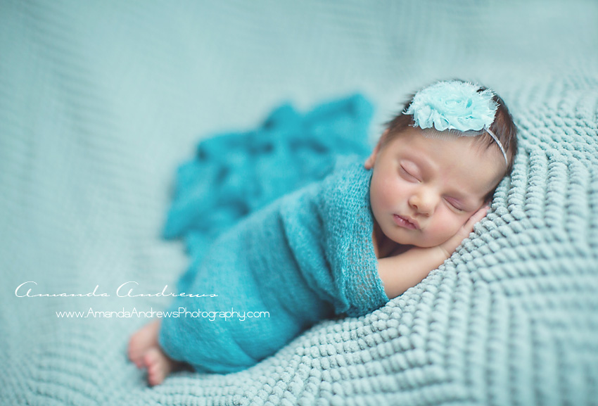 infant wrapped in blue scarf