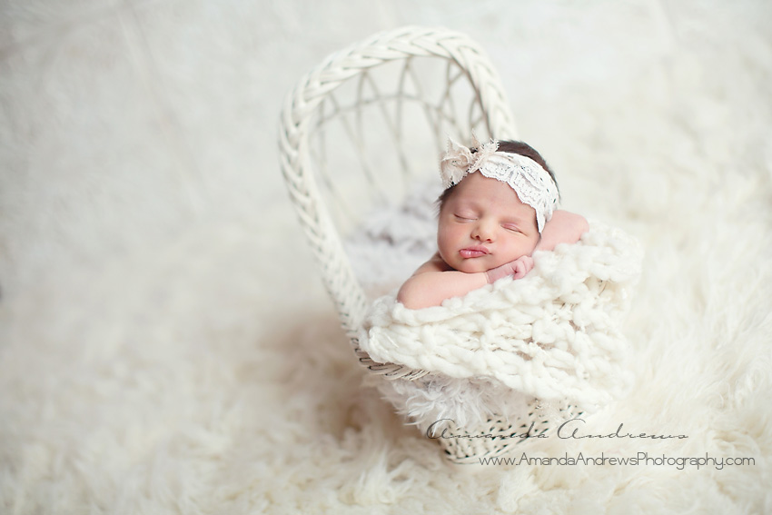 newborn sleeping in white bassinet