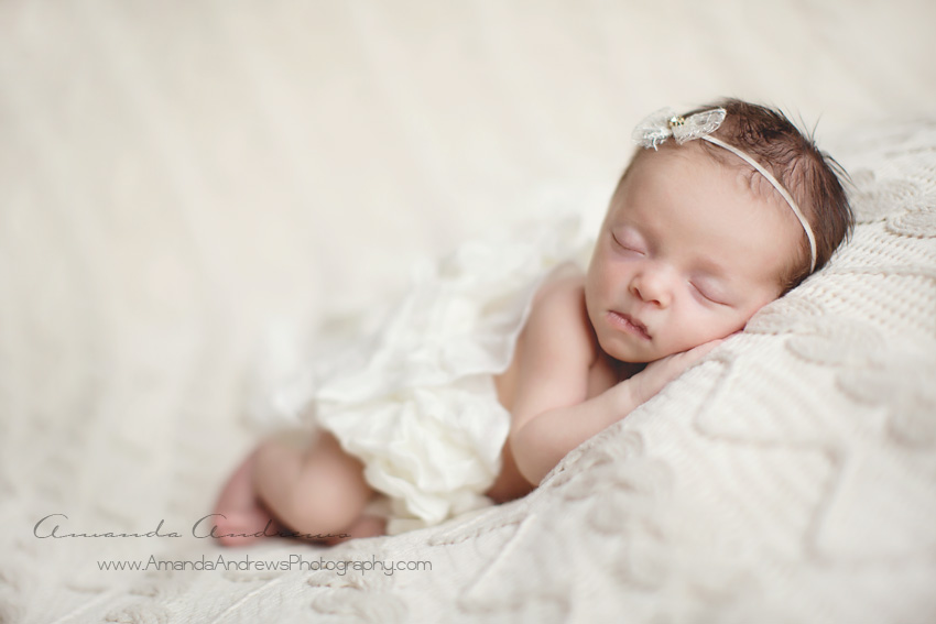 baby wrapped in white sleeping on cable knit blanket