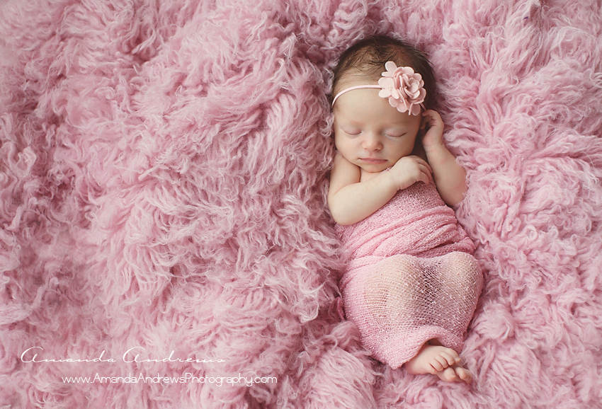 newborn baby asleep on pink fur