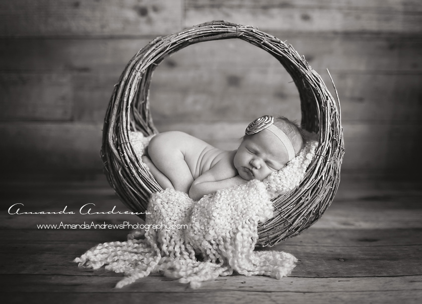 black and white photo of baby in circle basket