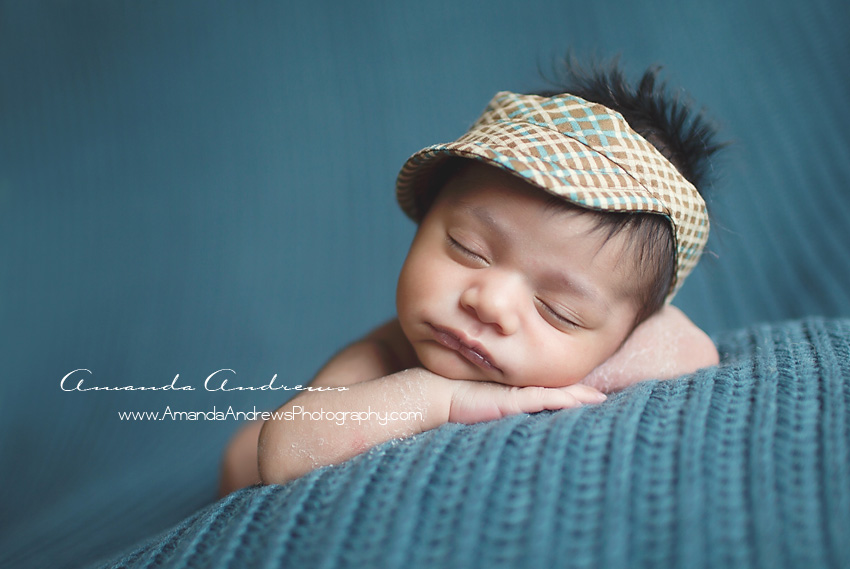 infant sleeping on blue blanket with hat on