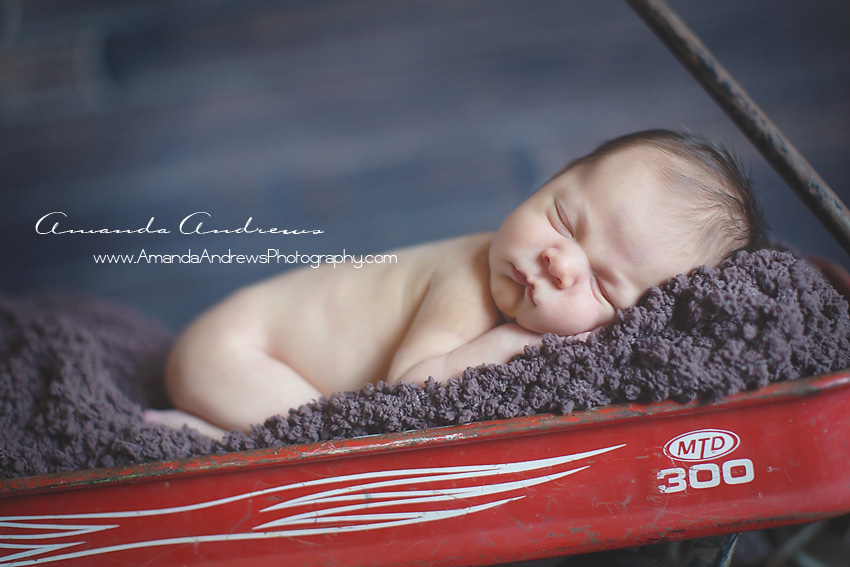 newborn asleep in red wagon