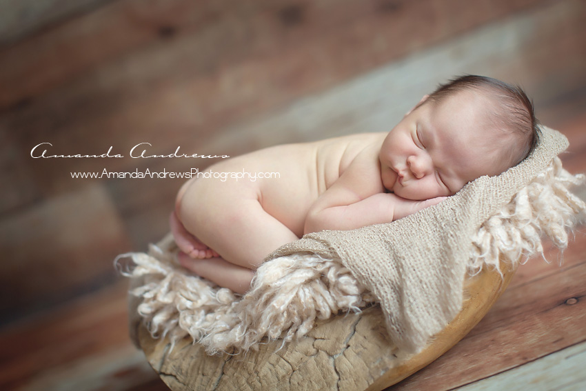 baby boy sleeping in wooden bowl