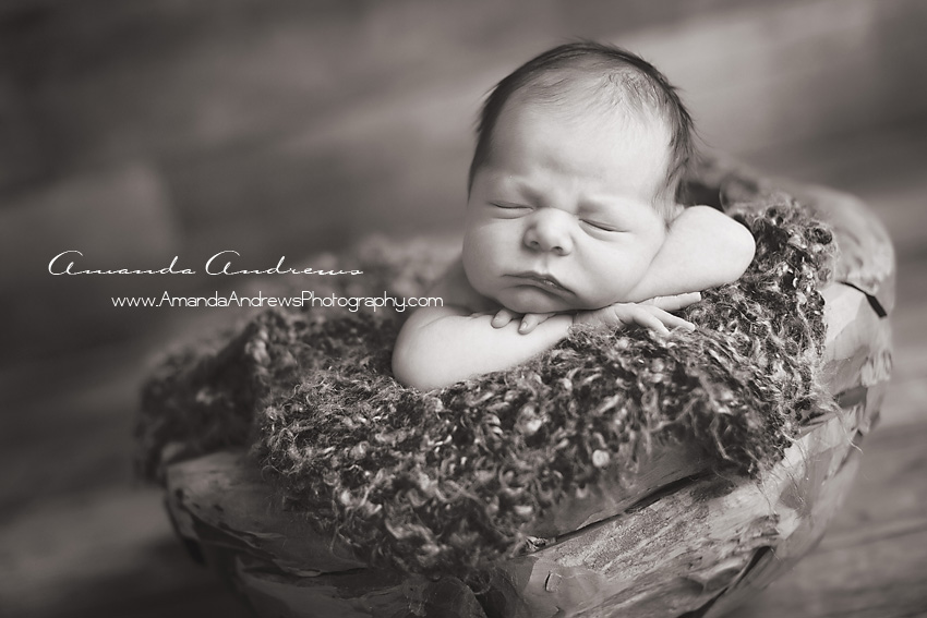 infant sleeping in wood bowl