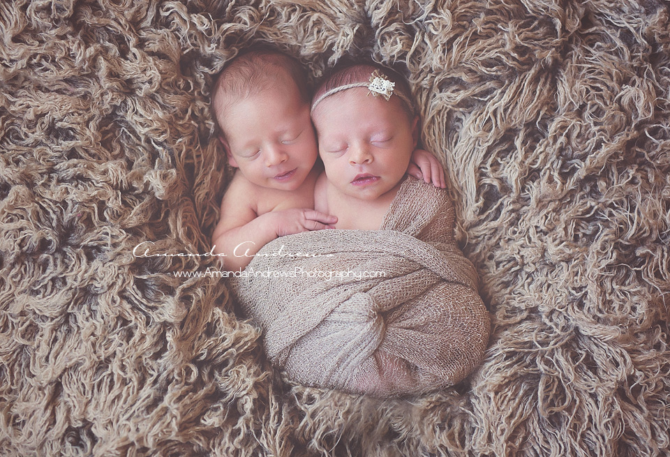 newborn twins with arms around eachother