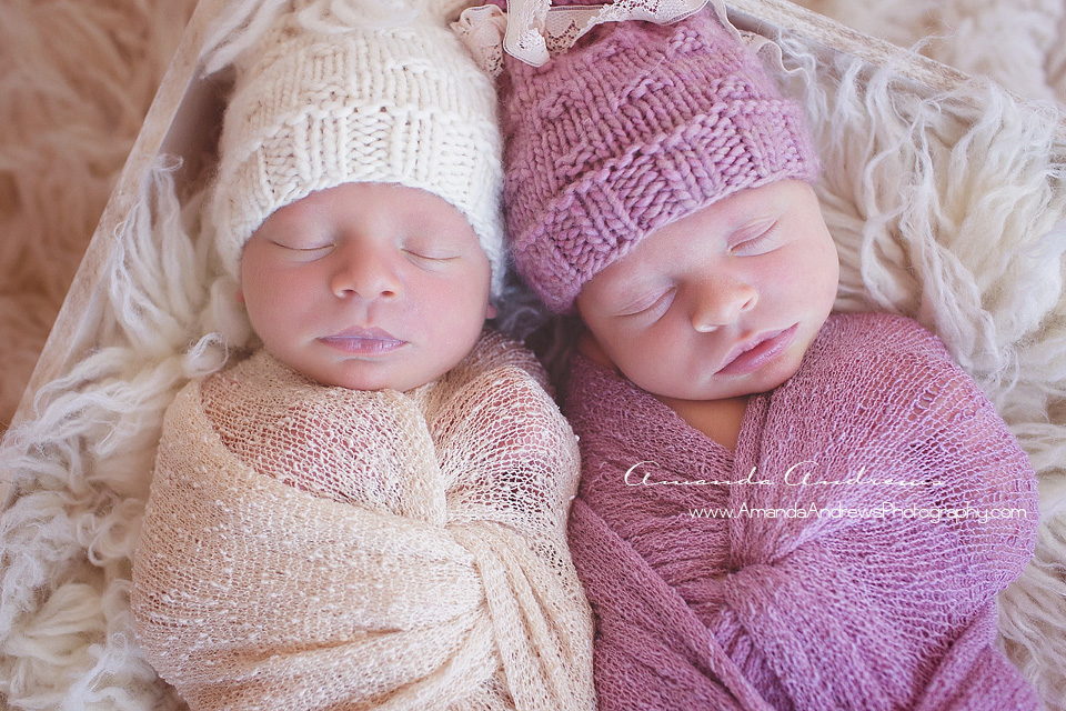twin newborns wrapped with hats